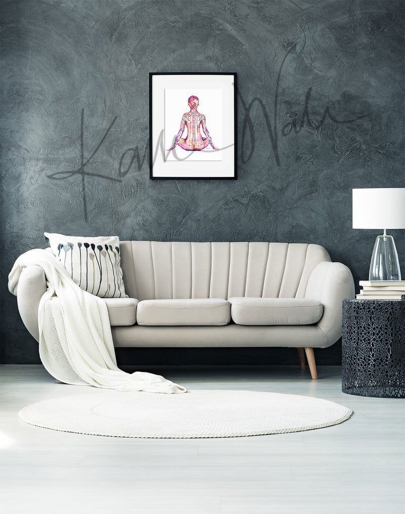 Framed watercolor painting of a person sitting in a meditative pose with meridian paths showing. The painting is hanging over a white couch.
