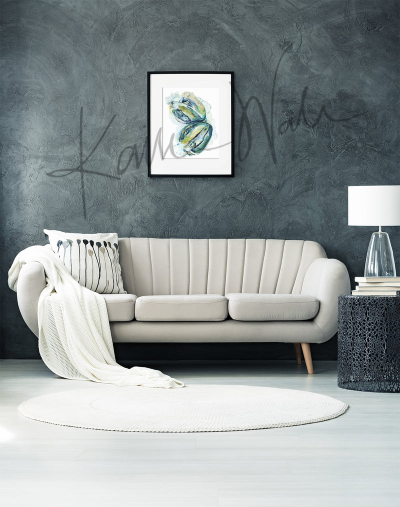 Framed watercolor painting of a heart dissection in greens blues and yellows.. The painting is hanging over a white couch.