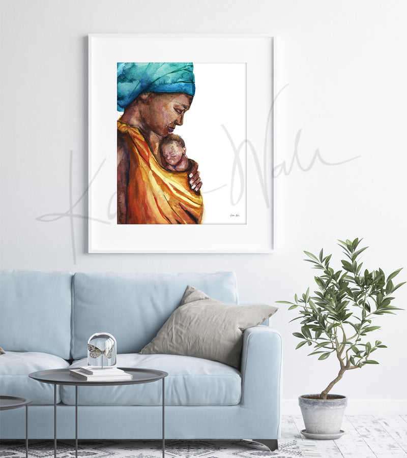 Framed watercolor painting of an african woman holding her premature infant. The painting is hanging over a blue couch.
